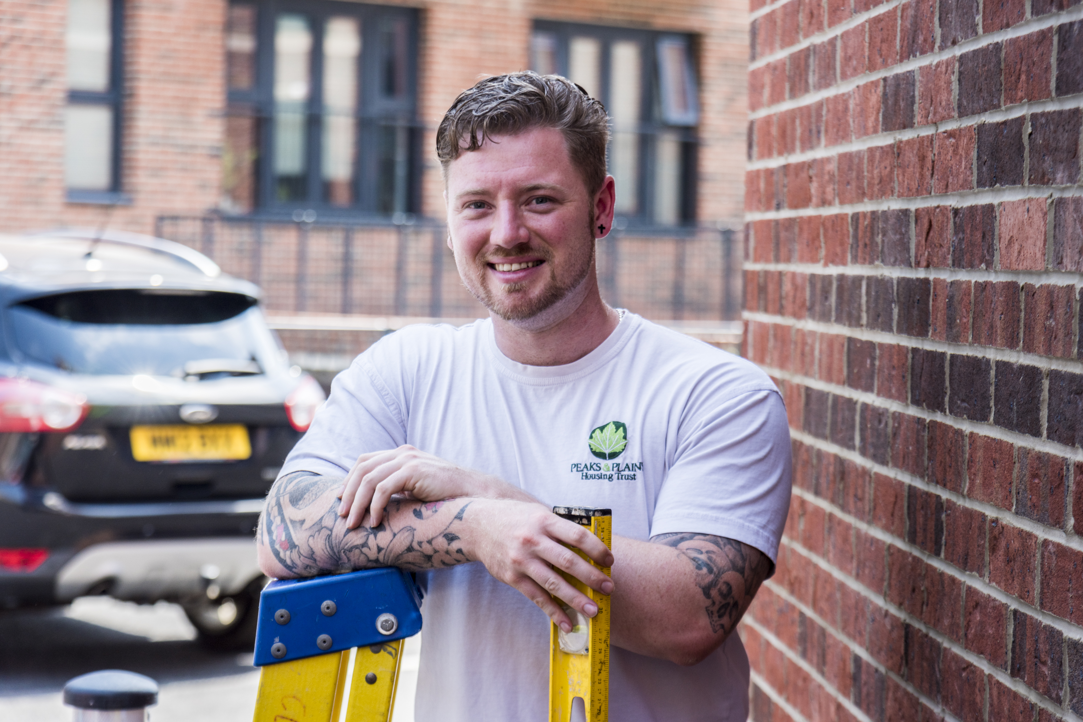 An inspector arrives at one of our homes. He holds a spirit level and leans on a ladder