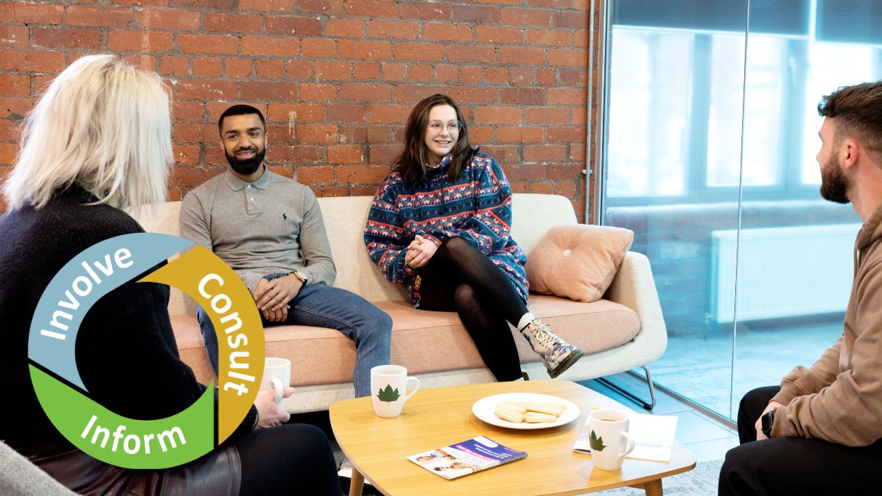 Four people sit around a coffee table talking